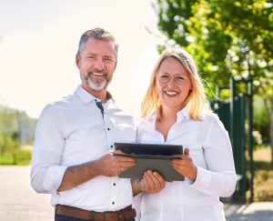 Gründer Herrmann Schlichtmann und Prozessmanagerin Verene Teigeler halten ein Tablet und schauen in die Kamera.